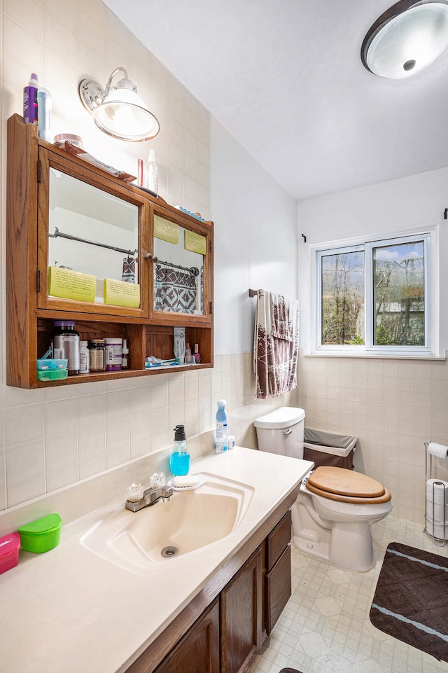 bathroom with tile patterned flooring, vanity, toilet, and tile walls