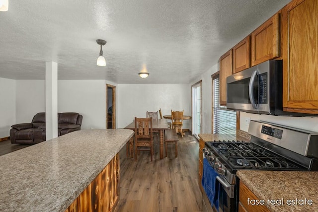 4731 N Osborn Rd, Riverdale, MI 48877 - kitchen featuring brown cabinets, a textured ceiling, appliances with stainless steel finishes, and wood finished floors