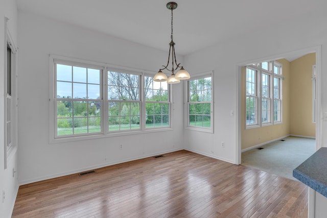 9080 Emerson Dr, Saline, MI 48176 - unfurnished dining area with an inviting chandelier, light wood finished floors, baseboards, and visible vents