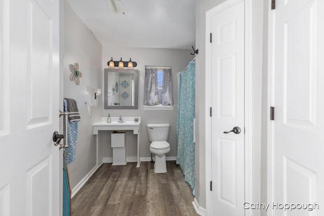 bathroom featuring a shower with curtain, visible vents, wood finished floors, baseboards, and toilet