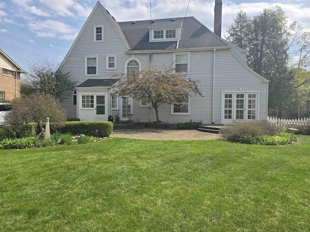 back of house featuring a lawn, fence, and a chimney