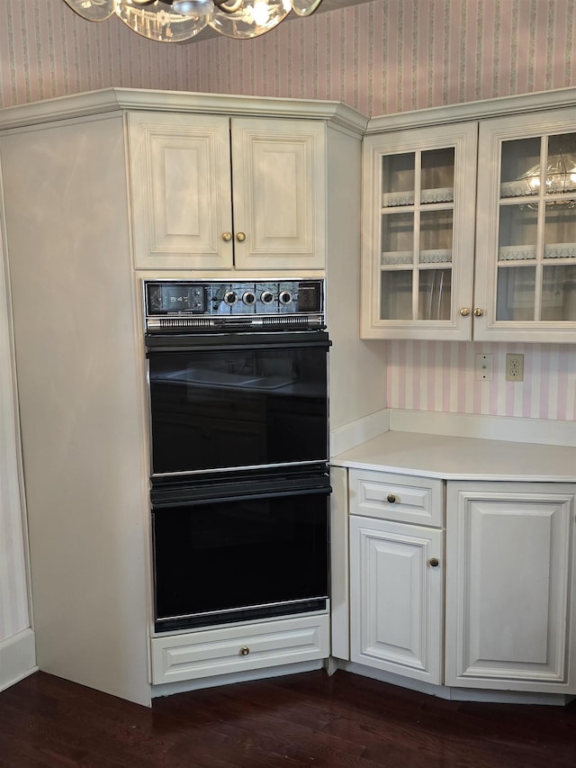 kitchen with glass insert cabinets, dobule oven black, and wallpapered walls
