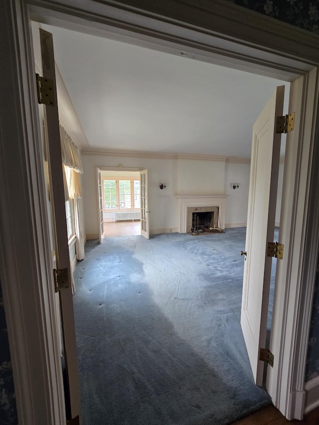 unfurnished living room with carpet flooring, crown molding, baseboards, and a fireplace