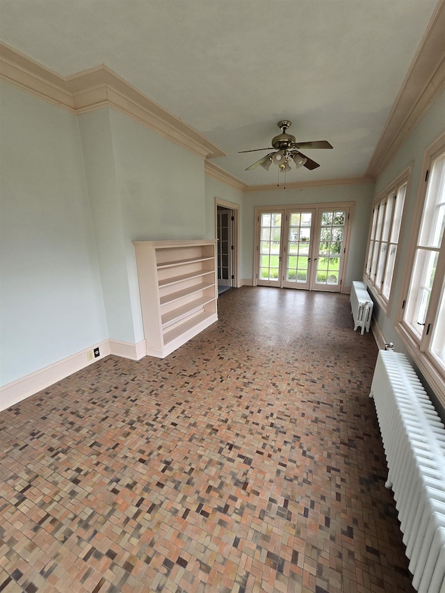unfurnished living room with crown molding, baseboards, ceiling fan, and radiator