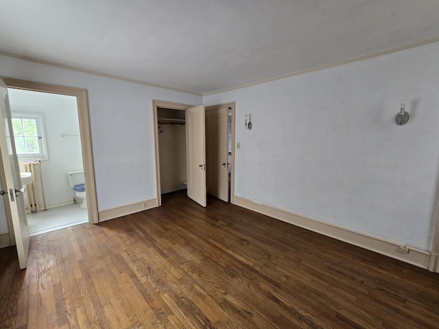 unfurnished bedroom featuring baseboards, a closet, connected bathroom, and dark wood-type flooring