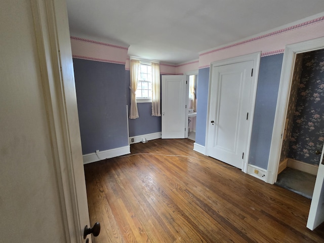 unfurnished bedroom with baseboards, connected bathroom, and wood finished floors