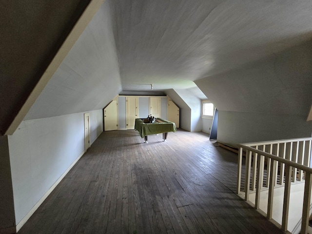 bonus room with dark wood finished floors and vaulted ceiling