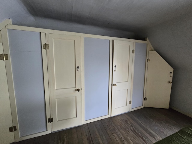 additional living space featuring dark wood finished floors and lofted ceiling