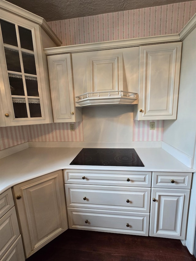 kitchen with light countertops, black electric cooktop, wallpapered walls, and custom exhaust hood