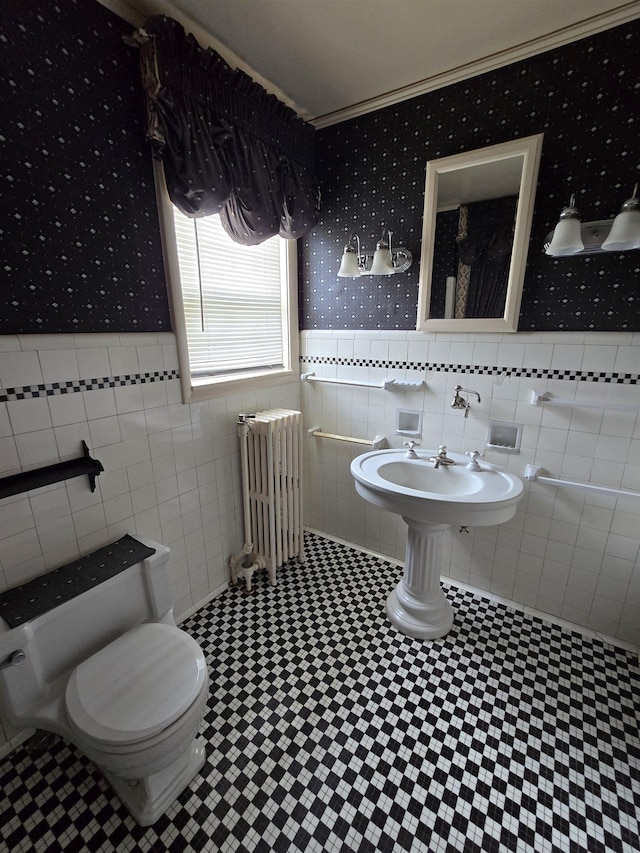 bathroom with radiator, wainscoting, wallpapered walls, and tile walls