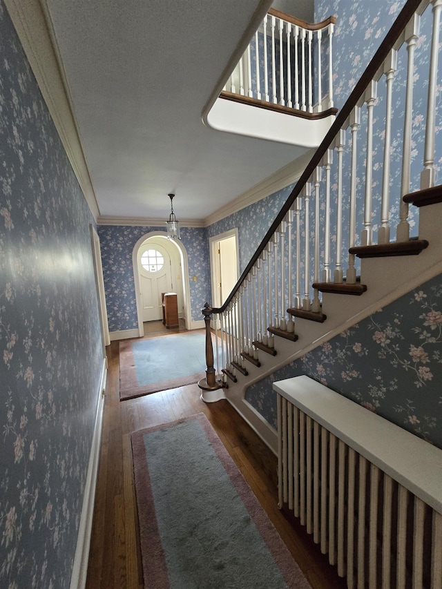 entryway with ornamental molding, wallpapered walls, hardwood / wood-style flooring, and stairs