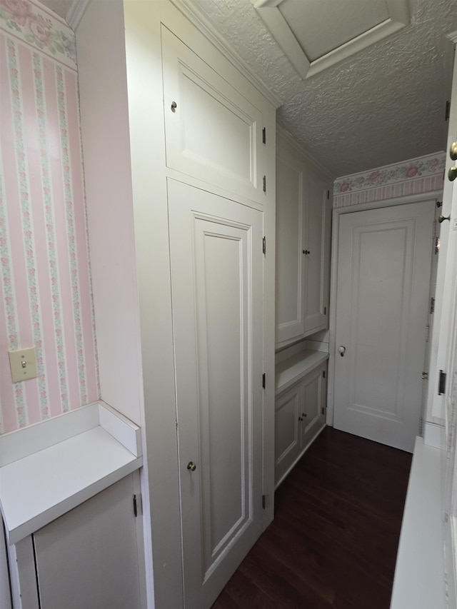mudroom with wallpapered walls, attic access, dark wood-style flooring, and a textured ceiling
