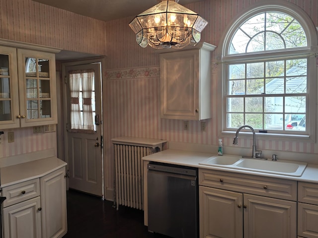 kitchen with glass insert cabinets, wallpapered walls, light countertops, a sink, and dishwasher