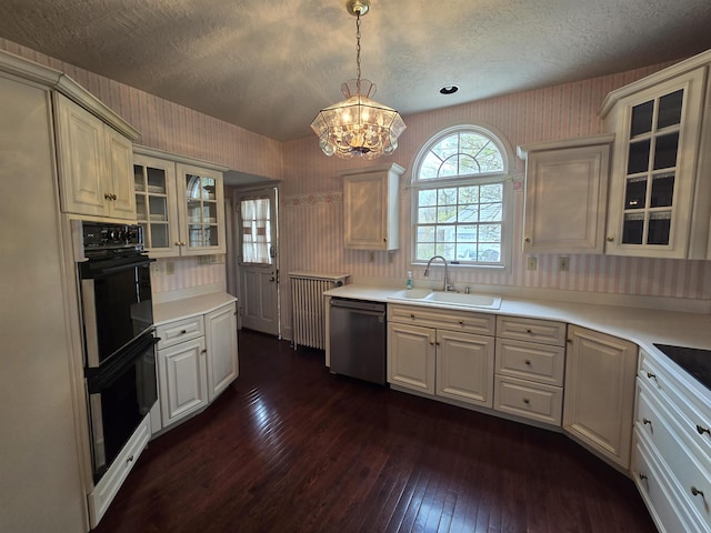 kitchen with a sink, black appliances, dark wood-style floors, a notable chandelier, and wallpapered walls
