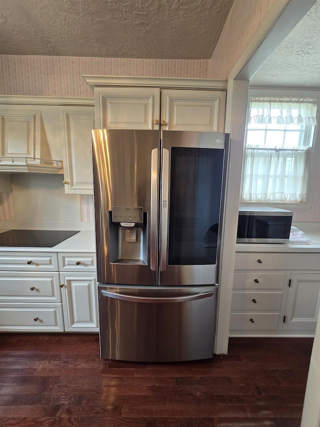 kitchen with a textured ceiling, appliances with stainless steel finishes, dark wood finished floors, and wall chimney exhaust hood