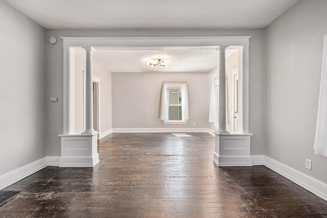 empty room featuring ornate columns, baseboards, hardwood / wood-style flooring, and visible vents