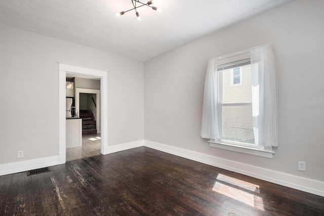 empty room with visible vents, stairway, baseboards, wood-type flooring, and an inviting chandelier