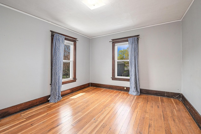 empty room with baseboards, plenty of natural light, ornamental molding, and hardwood / wood-style flooring