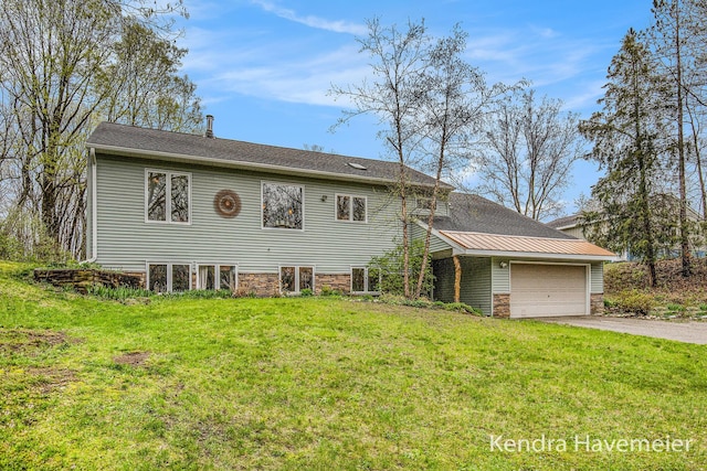 back of property featuring a lawn, a garage, and aphalt driveway