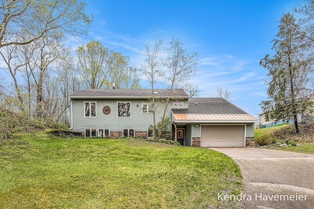 split level home featuring an attached garage, driveway, stone siding, and a front lawn