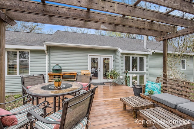 wooden terrace with outdoor dining area, a pergola, and french doors