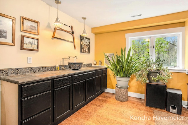 bathroom with visible vents, double vanity, wood finished floors, baseboards, and a sink