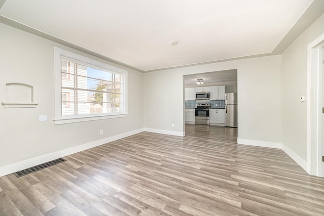 507 S Lincoln St, Bay City, MI 48708 - unfurnished living room featuring visible vents, light wood finished floors, and baseboards