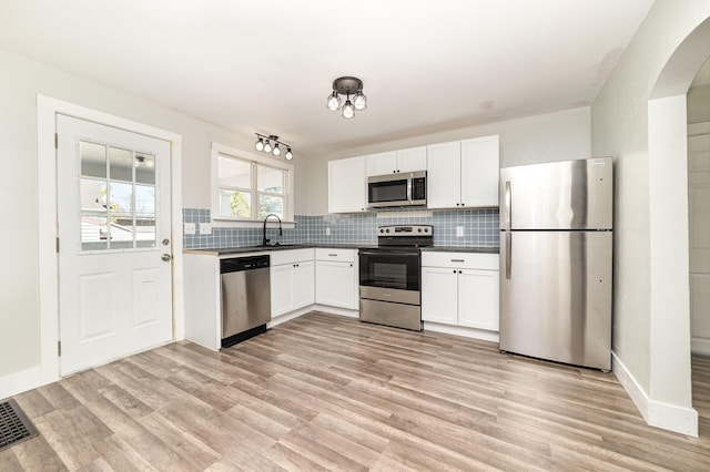 507 S Lincoln St, Bay City, MI 48708 - kitchen featuring white cabinets, a sink, light wood-style floors, stainless steel appliances, and tasteful backsplash