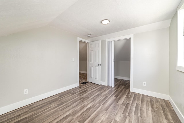 507 S Lincoln St, Bay City, MI 48708 - unfurnished bedroom with a closet, lofted ceiling, wood finished floors, baseboards, and a textured ceiling