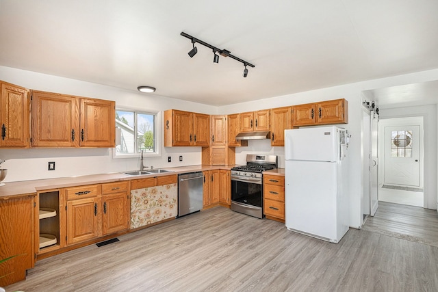 kitchen with a sink, stainless steel appliances, light wood-type flooring, visible vents, and under cabinet range hood