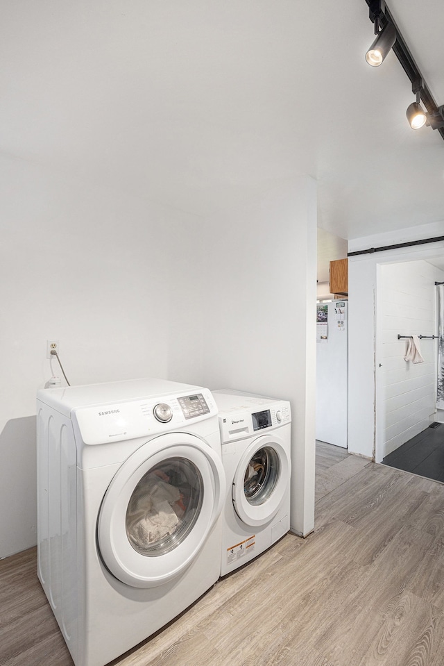 clothes washing area with washer and dryer, laundry area, and wood finished floors
