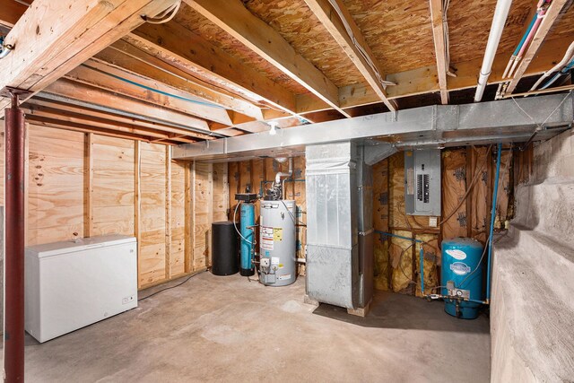 unfinished below grade area featuring fridge, water heater, electric panel, and heating unit