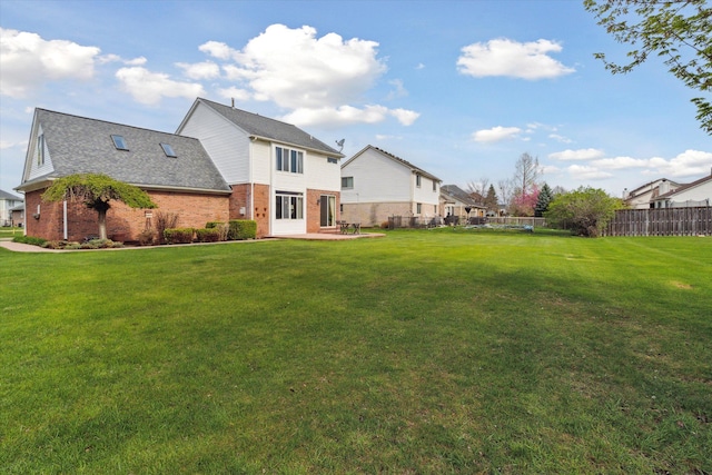 rear view of house featuring a lawn, fence, a patio, and brick siding