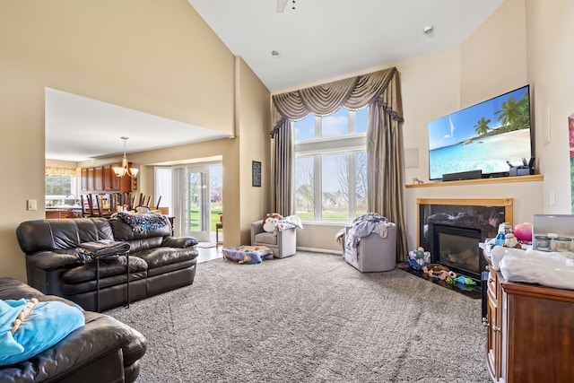 living area with carpet flooring, high vaulted ceiling, a notable chandelier, and a high end fireplace