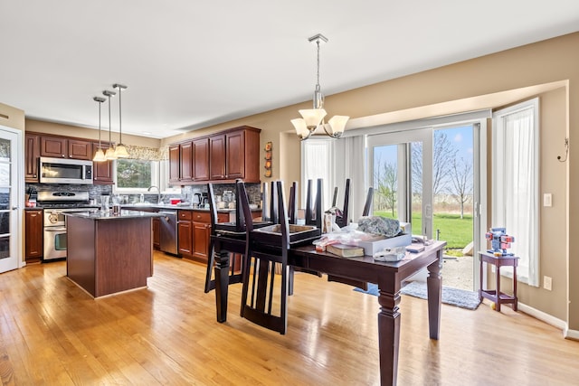 kitchen with an inviting chandelier, light wood-style flooring, appliances with stainless steel finishes, and backsplash