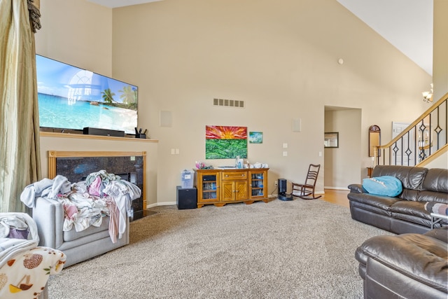 carpeted living room featuring high vaulted ceiling, visible vents, stairway, and a high end fireplace