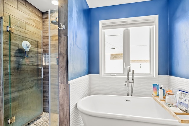 bathroom featuring wainscoting, a soaking tub, and a shower stall