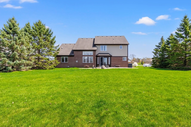 rear view of house with brick siding, a yard, and a patio