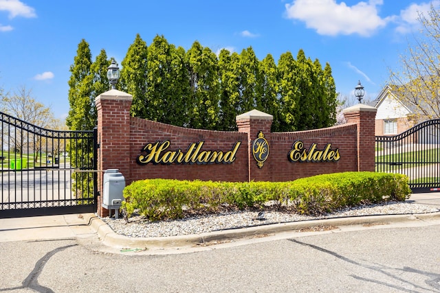 community / neighborhood sign featuring a gate and fence