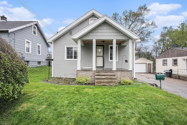 bungalow-style home with stone siding, a garage, a porch, a front yard, and an outbuilding