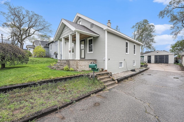 view of front facade featuring aphalt driveway, a garage, a front yard, a chimney, and an outdoor structure