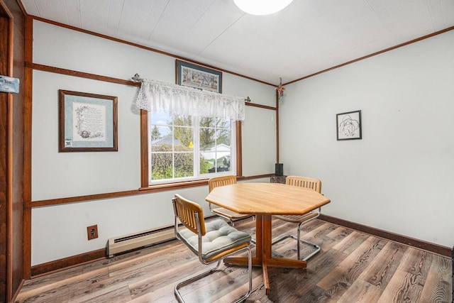 dining space with baseboards, ornamental molding, and wood finished floors