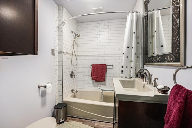 full bath featuring vanity, shower / tub combo with curtain, toilet, wood finished floors, and visible vents