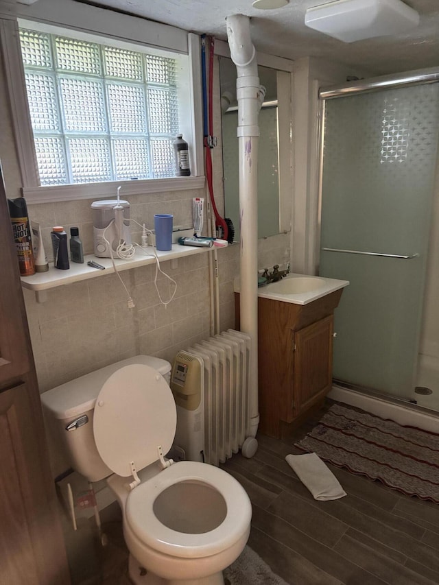full bath featuring radiator, a shower stall, toilet, and wood finished floors