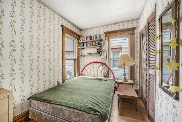 bedroom featuring hardwood / wood-style flooring, multiple windows, and wallpapered walls