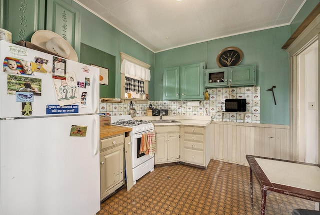 kitchen with crown molding, white appliances, light countertops, dark floors, and a wainscoted wall