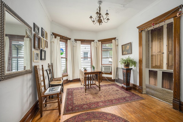 sitting room with wood-type flooring, baseboards, an inviting chandelier, and crown molding