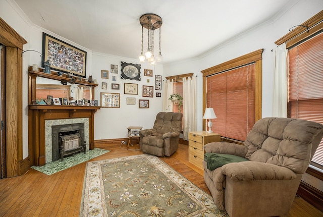 living area featuring wood-type flooring, baseboards, ornamental molding, and a tiled fireplace
