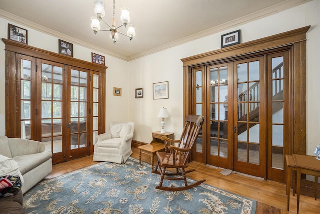 sitting room with crown molding, a chandelier, french doors, baseboards, and wood finished floors