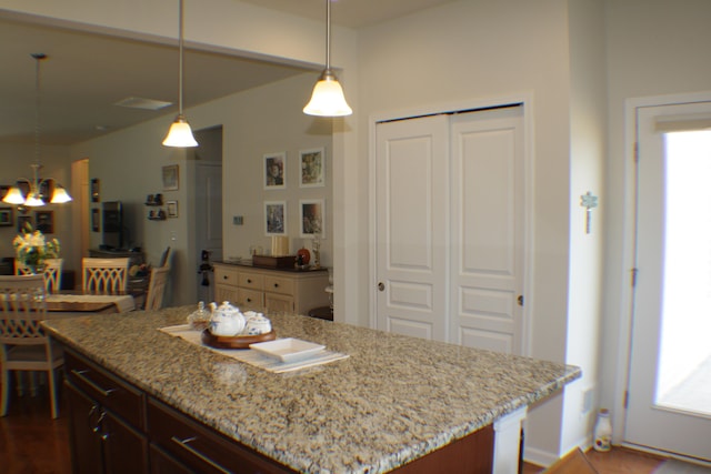 kitchen featuring light stone counters, hanging light fixtures, and a notable chandelier